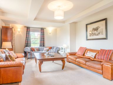 A living room with leather sofas a wooden coffee table and a lion picture at Hilltop House in Tenbury Wells