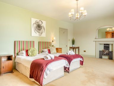 A bedroom with two single beds with striped headboards and red throws at Hilltop House in Tenbury Wells