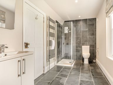A bathroom with a sink cabinet door toilet shower enclosure and a towel radiator at Hilltop House in Tenbury Wells