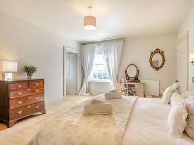 A bedroom with a bed folded towels a wooden dresser and a vanity table with a mirror at Hilltop House in Tenbury Wells