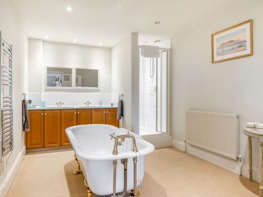 A bathroom with a freestanding bathtub a double sink vanity a shower and a radiator at Hilltop House in Tenbury Wells