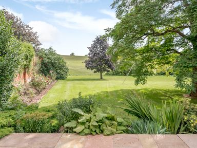 A garden with a lawn trees shrubs and flowers at Hilltop House in Tenbury Wells