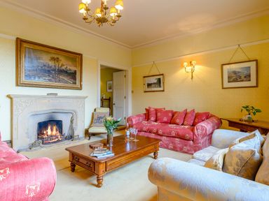 A living room with sofas a wooden coffee table and a fireplace at Hilltop House in Tenbury Wells