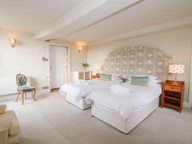 A bedroom with two single beds with patterned headboard and bedside tables with lamps at Hilltop House in Tenbury Wells