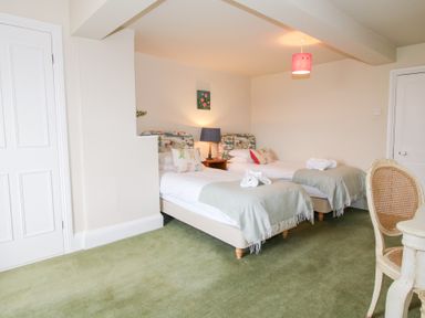 A bedroom with two single beds with light green throws and a chair at Hilltop House in Tenbury Wells