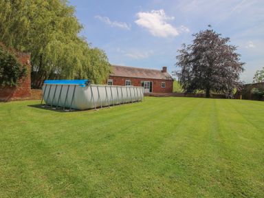 A garden with a swimming pool and trees at Hilltop House in Tenbury Wells