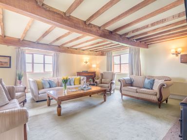 A living room with sofas chairs a wooden coffee table and exposed wooden beams at The Chestnuts in Tenbury Wells
