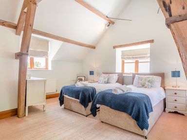 A bedroom with two single beds with blue blankets and pillows wooden beams on the ceiling at The Chestnuts in Tenbury Wells