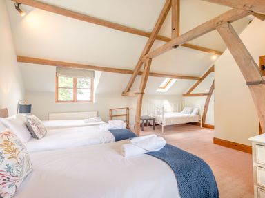 A bedroom with three single beds under wooden ceiling beams at The Chestnuts in Tenbury Wells
