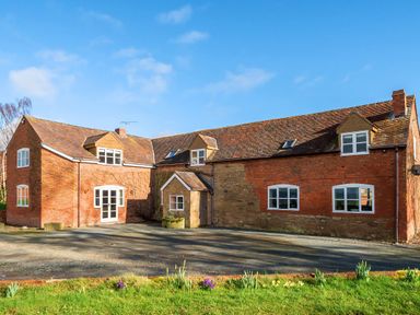 A brick house with multiple windows and a gravel driveway at The Chestnuts in Tenbury Wells