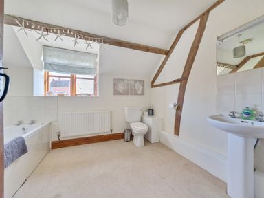 A bathroom with a bathtub a toilet a sink and a window with a patterned blind at The Chestnuts in Tenbury Wells