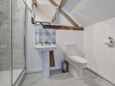 A bathroom with a shower cubicle sink toilet and exposed wooden beams at The Chestnuts in Tenbury Wells