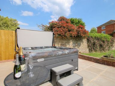 An outdoor patio with a hot tub a small metal table with champagne bottles and glasses at The Chestnuts in Tenbury Wells