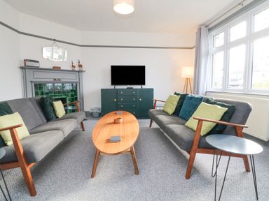 A living room with two gray sofas with cushions a wooden coffee table a gray fireplace and a television on a cabinet at Chilton in Bude