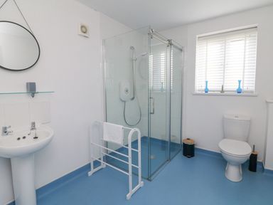 A bathroom with a shower enclosure a pedestal sink a toilet and a towel rack at Chilton in Bude
