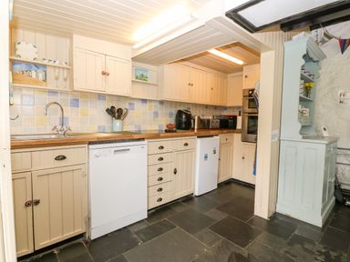 A kitchen with cream cabinets appliances and a light blue cabinet on the right at Tyddyn Serri in Rhosneigr