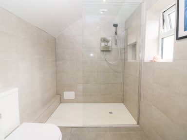 A bathroom with a walk in shower a toilet and a window at Tyddyn Serri in Rhosneigr