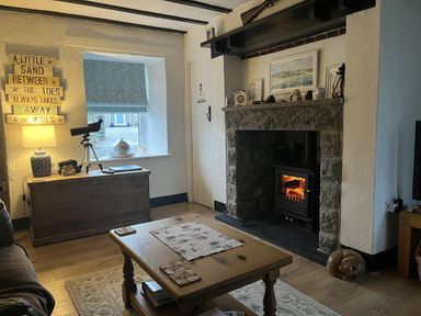 A living room with a fireplace and telescope at Tyddyn Serri in Rhosneigr