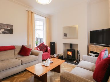 A living room with sofas a coffee table a television and a wood burning stove at Beach House in Bridlington