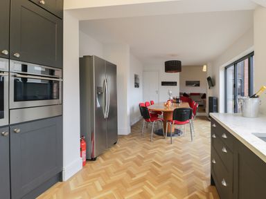 A kitchen and dining area with wooden flooring red chairs and stainless steel appliances at Beach House in Bridlington