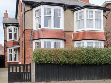 Exterior view of a two story semi detached house with bay windows hedge and black wooden fence at Beach House in Bridlington