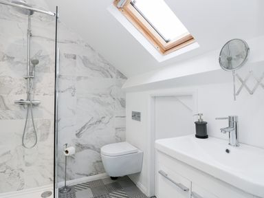 A bathroom with a shower, wall-mounted toilet, sink, and skylight at Beach House in Bridlington