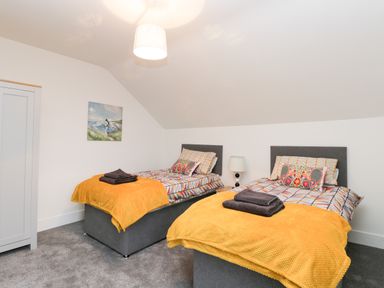 A bedroom with two single beds with yellow blankets and folded towels at Beach House in Bridlington