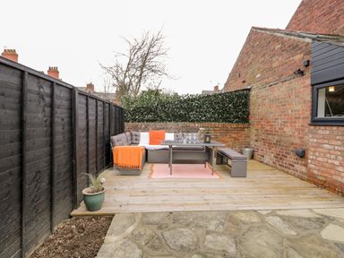An outdoor patio area with a wooden deck seating table bench and potted plant at Beach House in Bridlington