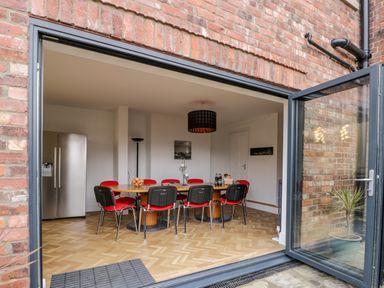 A dining room with a large wooden table surrounded by red and black chairs next to a stainless steel refrigerator at Beach House in Bridlington