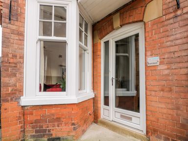 A brick exterior wall with a white framed bay window and a white door with glass panels at Beach House in Bridlington