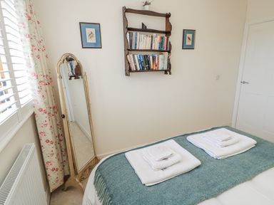 A bedroom with a bed, towels on the bed, and bookshelves at Keepers Cottage in West Knoyle