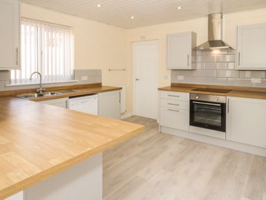 A kitchen with wooden countertops an oven and stovetop a sink dishwasher and cabinets at Arwelfa in Penmaenmawr