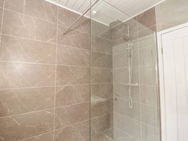 A shower area with glass partition and wall-mounted showerhead in a bathroom at Arwelfa in Penmaenmawr
