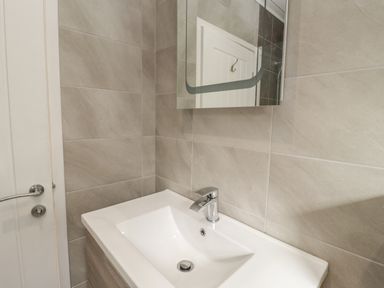 A bathroom sink with a chrome faucet and a wall-mounted mirror above it at Arwelfa in Penmaenmawr
