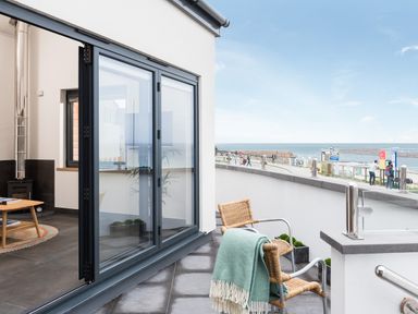 A balcony with two chairs and a green blanket overlooking the sea at The Old Beach Store in Sennen Cove