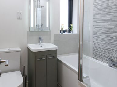 A bathroom with a toilet sink cabinet and bathtub with shower at Tarn Lodge in Bowness-On-Windermere