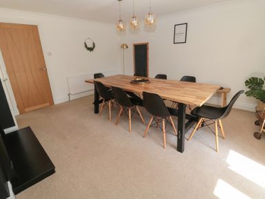 A dining room with a wooden table and black chairs at Changing Tide in Beadnell