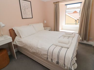 A bedroom with a bed with white bedding and two bedside tables with lamps at Changing Tide in Beadnell