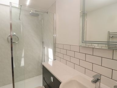 A bathroom with a shower area and a sink with a faucet at Changing Tide in Beadnell