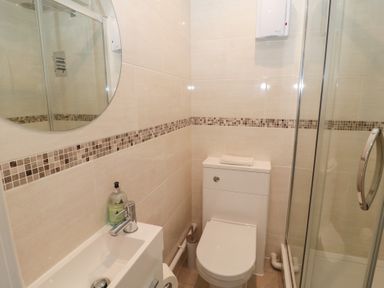 A bathroom with a toilet sink shower and round mirror at Changing Tide in Beadnell