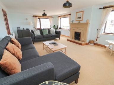A living room with two gray sofas a coffee table and a fireplace at Changing Tide in Beadnell