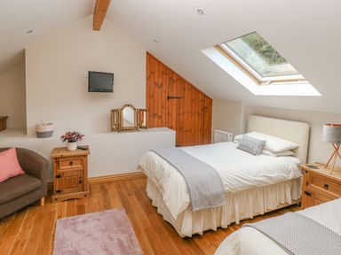 A bedroom with two single beds a wooden floor a skylight window and wooden furniture at Little Brook Cottage in Laugharne