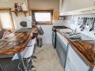 A kitchen with wooden countertops a stove a sink and kitchen utensils hanging on the wall at Castle View Cabin in Cloughton