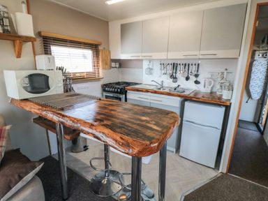 A kitchen with wooden countertop island stools microwave and stove at Castle View Cabin in Cloughton