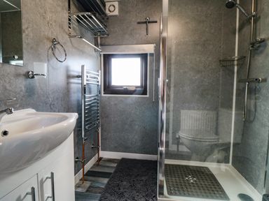 A bathroom with a sink vanity towel rack window and a glass shower enclosure at Castle View Cabin in Cloughton
