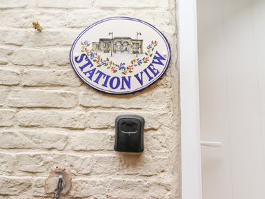 A white brick wall with a ceramic house name plaque reading Station View and a black doorbell at Station View in Whitby