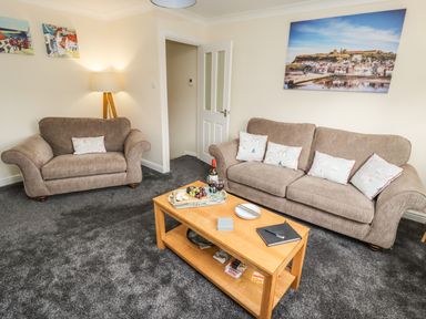 A living room with two sofas a wooden coffee table with snacks and wine and wall art at Station View in Whitby