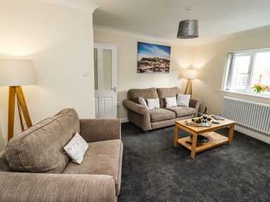 A living room with two sofas a wooden coffee table two lamps and a window at Station View in Whitby