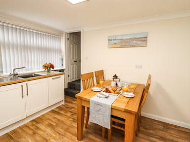 A kitchen with a wooden dining table set for breakfast with croissants and orange juice at Station View in Whitby