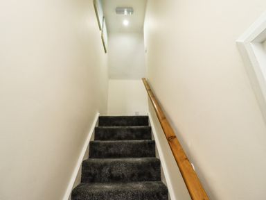 A carpeted staircase with a wooden handrail and white walls at Station View in Whitby